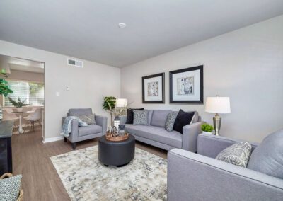 A cozy living room featuring gray couches arranged around a central coffee table, creating a welcoming atmosphere.