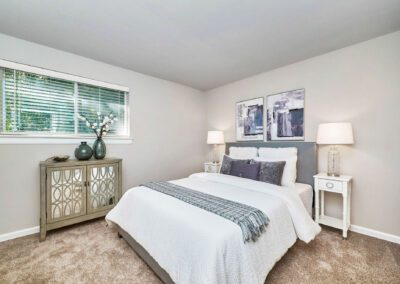 A tranquil bedroom with a well-arranged bed, a modern nightstand, and a window that enhances the room's ambiance.